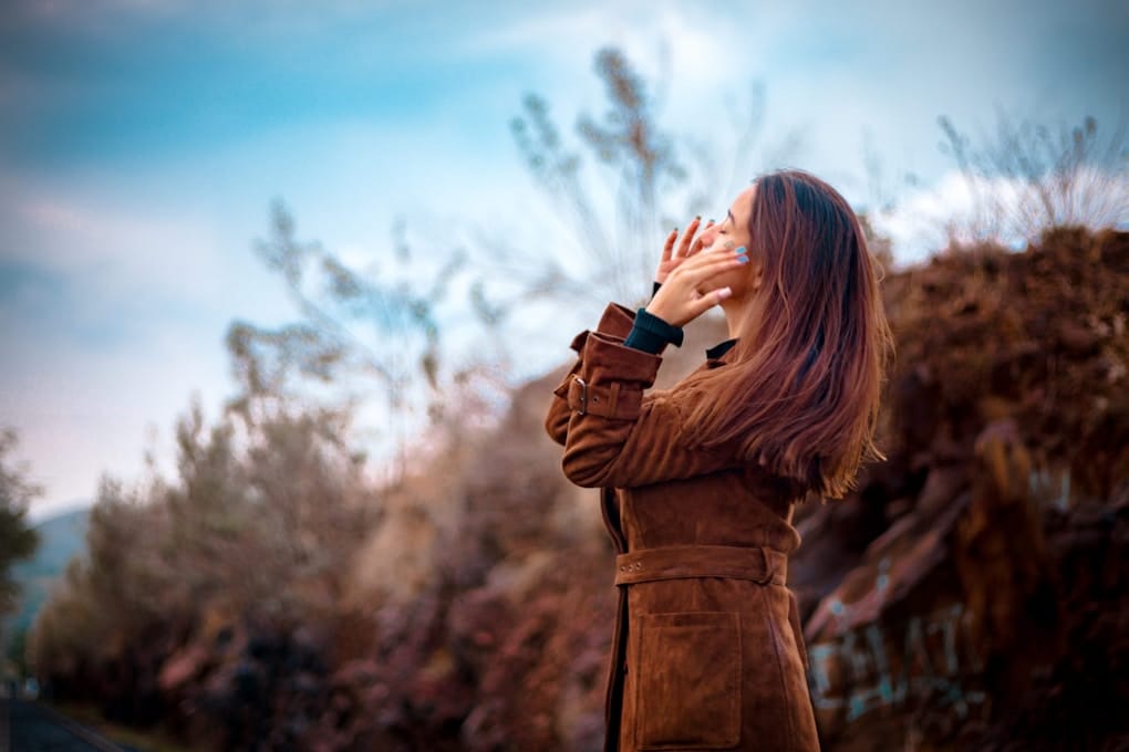 woman in brown coat holding black camera